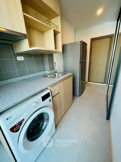 Modern kitchen with washing machine and fridge in compact layout