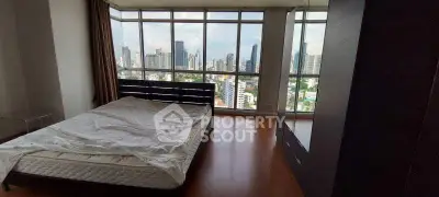 Spacious bedroom with panoramic city view and large windows in modern apartment.