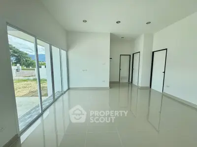 Spacious modern living room with large windows and glossy tiled floors