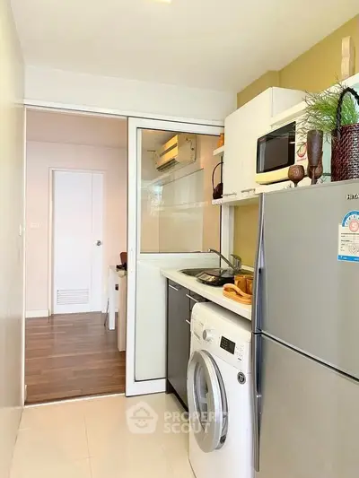 Modern kitchen with sleek appliances and washing machine in compact layout
