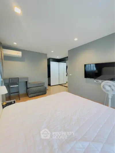 Modern bedroom with sleek design, featuring a wall-mounted TV and stylish furniture.