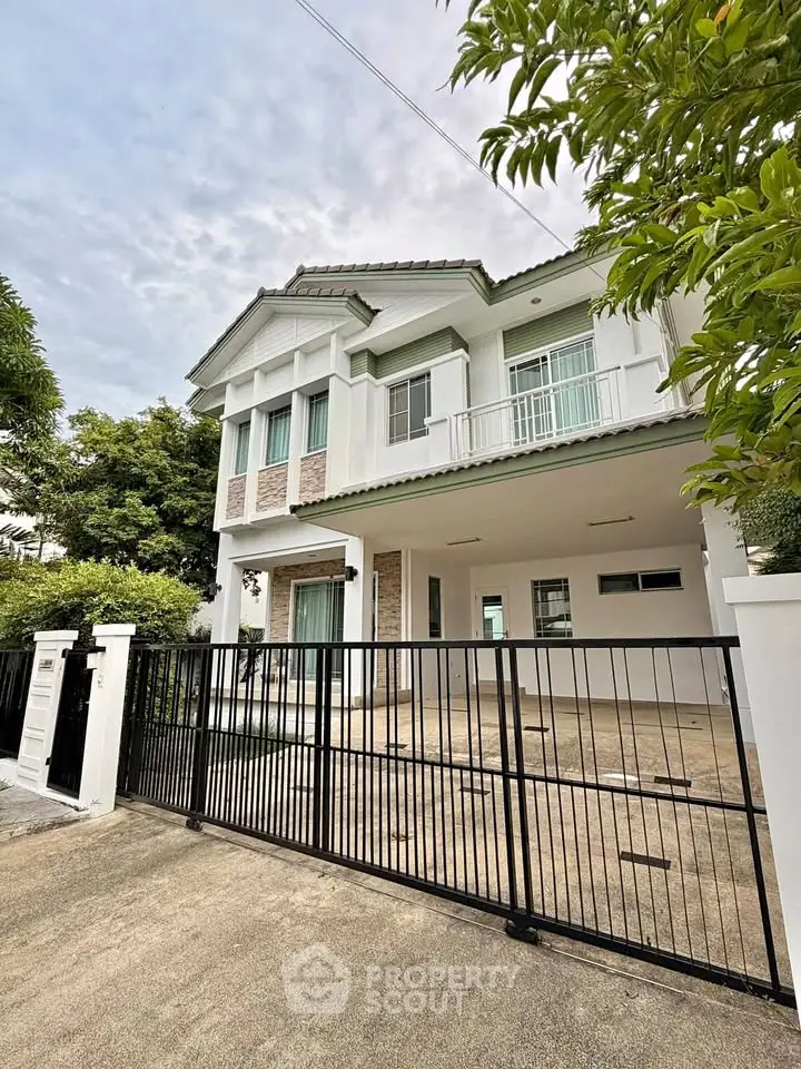 Elegant two-story house with modern design and spacious driveway, surrounded by lush greenery.