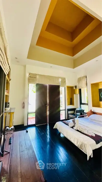 Luxurious bedroom with high ceiling and elegant decor, featuring large windows and a cozy bed.