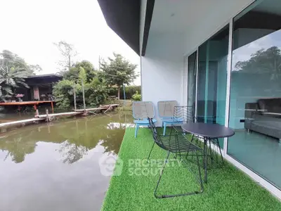 Charming riverside balcony with lush greenery and modern seating, perfect for relaxation.