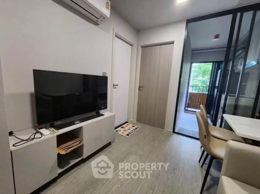 Modern living room with sleek TV setup and balcony view in stylish apartment.