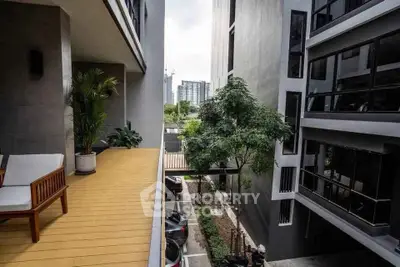 Modern apartment building with lush greenery and spacious balcony view.
