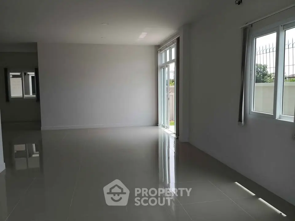 Spacious and bright living room with large windows and glossy tiled floors.