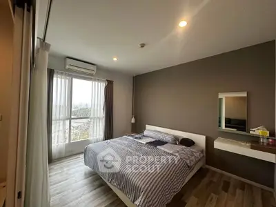 Modern bedroom with large window and stylish decor in a contemporary apartment.