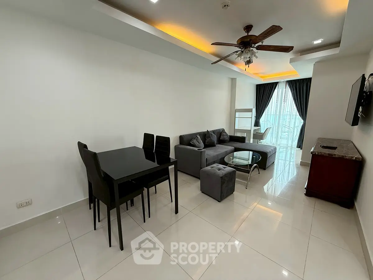 Modern living room with sleek furniture and ceiling fan, featuring large windows and stylish lighting.