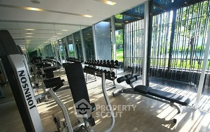 Modern gym with state-of-the-art equipment and floor-to-ceiling windows offering lush garden views.
