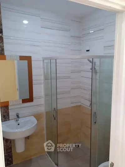 Modern bathroom with glass shower and sleek sink in stylish apartment.