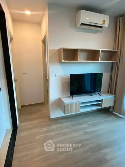 Modern living room with sleek TV stand and wall-mounted air conditioner in a cozy apartment.