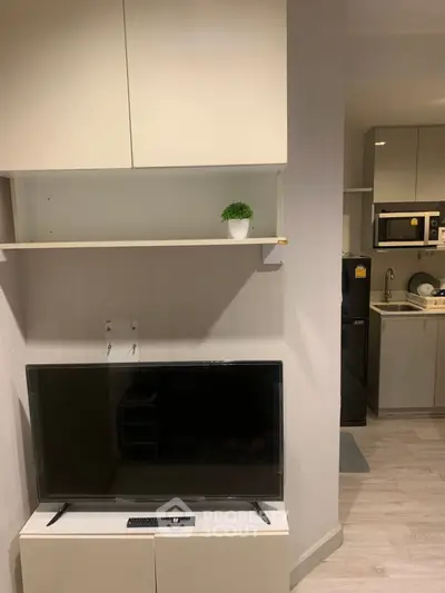 Modern living room with sleek TV setup and compact kitchen area, perfect for urban living.