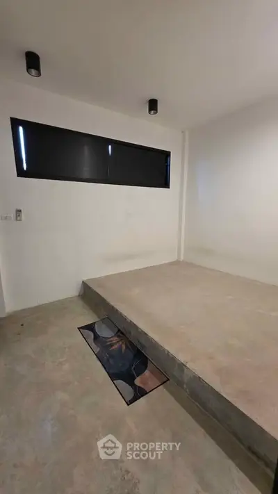 Minimalist bedroom with elevated concrete platform and modern lighting