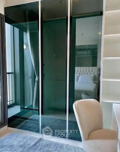 Modern bedroom with glass wardrobe and cozy chair in stylish apartment