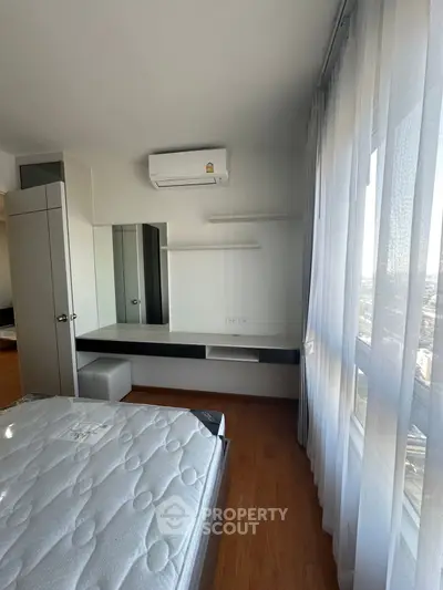 Modern bedroom with large window and air conditioning unit, featuring sleek furniture and wooden flooring.