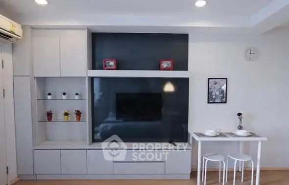 Modern living room with sleek TV unit and dining area in stylish apartment.