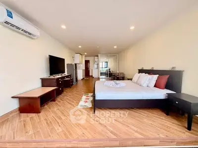 Spacious studio apartment with modern furnishings and open layout, featuring a cozy bed and sleek TV setup.
