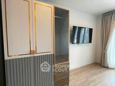 Modern bedroom with stylish wardrobe and wall-mounted TV, featuring elegant curtains and wooden flooring.
