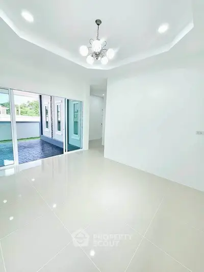 Spacious modern living room with elegant chandelier and sliding glass doors to patio.