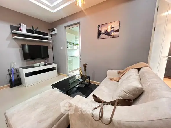 Cozy modern living room with plush sofa and wall-mounted TV, perfect for relaxation.