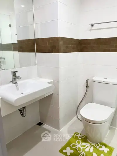 Modern bathroom with sleek white fixtures and stylish brown tile accents.