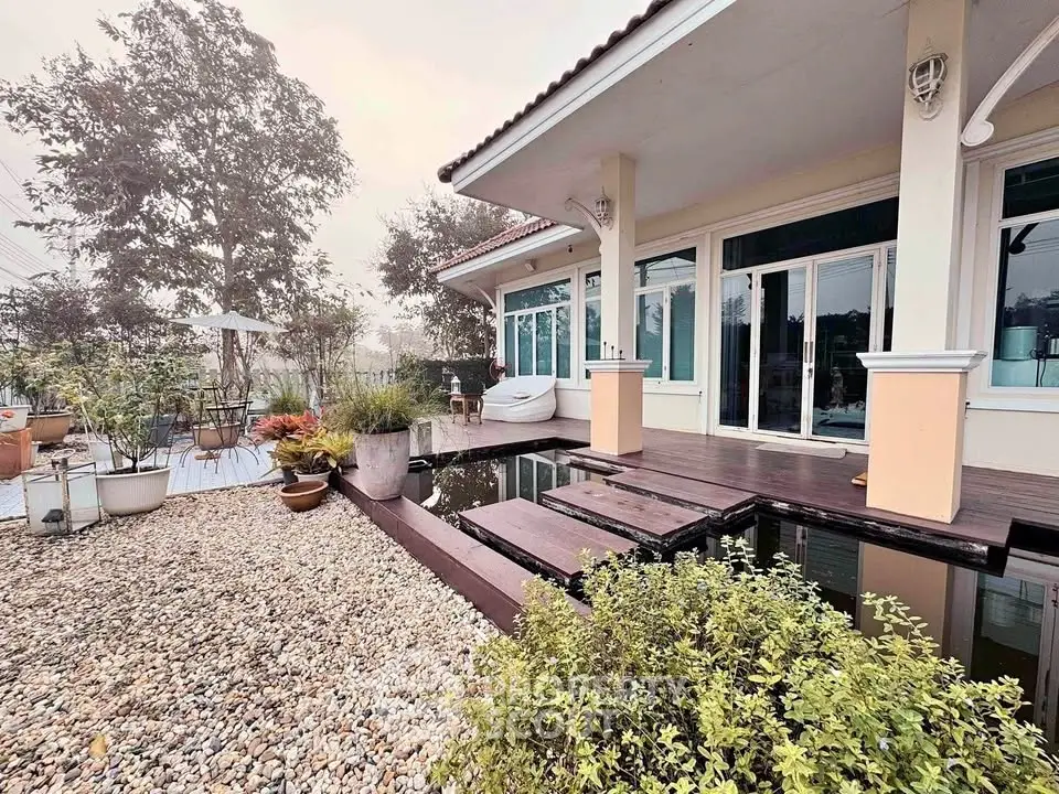 Charming modern home with serene garden and pond, featuring large windows and inviting outdoor space.