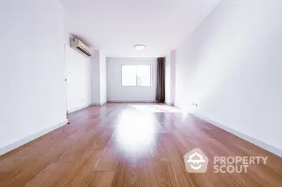 Spacious empty living room with wooden flooring and large window