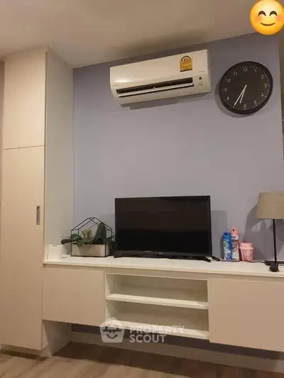 Modern living room with wall-mounted TV and air conditioner, featuring sleek storage and minimalist decor.