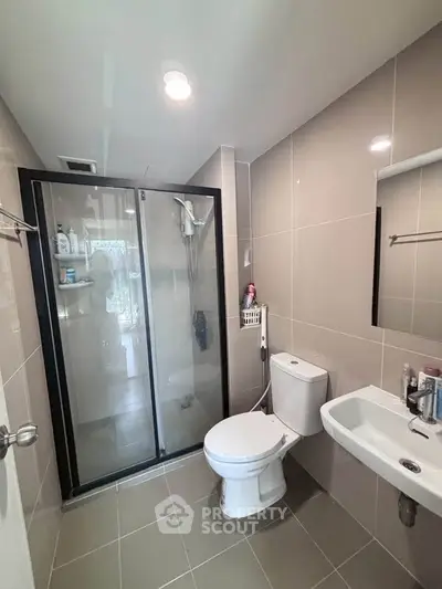 Modern bathroom with glass shower and sleek fixtures in contemporary apartment.