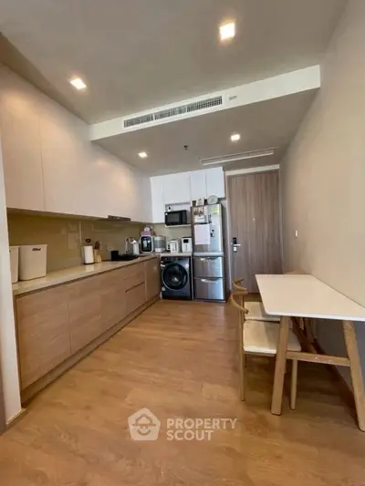 Modern kitchen with wooden flooring, sleek cabinets, and built-in appliances in a cozy apartment.