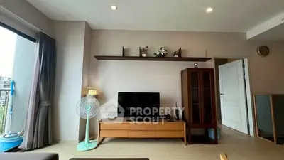 Modern living room with sleek TV stand and stylish decor, featuring a large window for natural light.