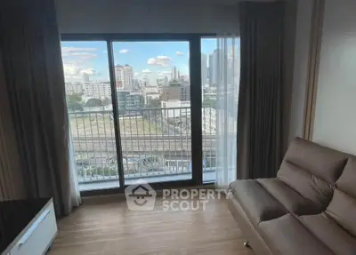 Modern living room with large window offering stunning city view and cozy seating area.