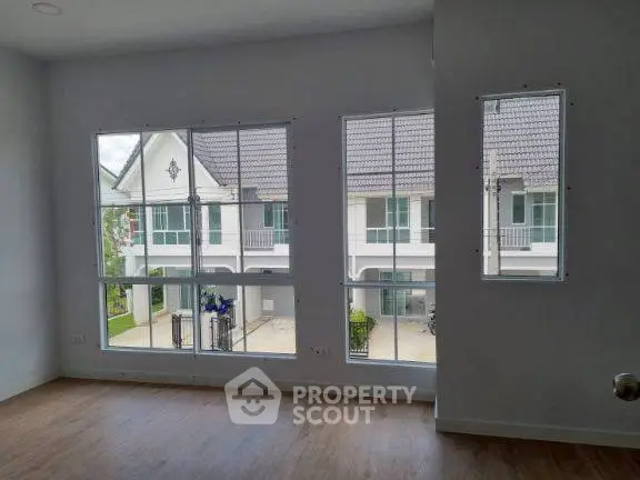 Spacious room with large windows offering a view of charming townhouses.