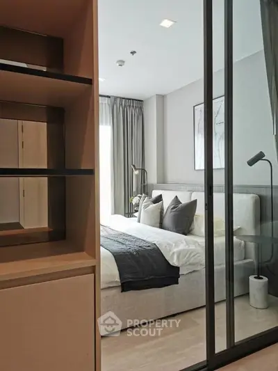 Modern bedroom with stylish decor and sliding glass doors, featuring cozy bedding and elegant lighting.