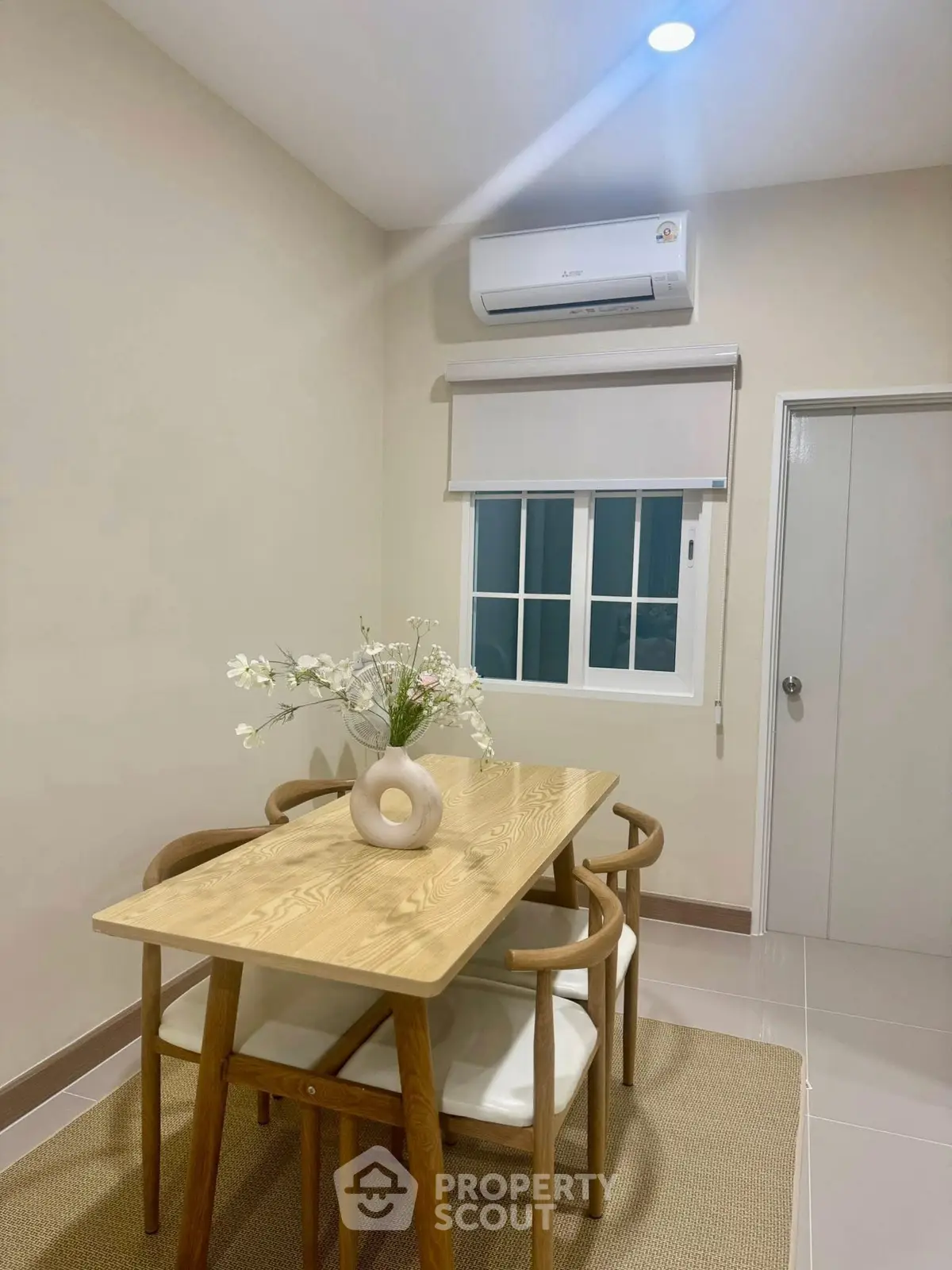 Modern dining area with wooden table and chairs, featuring minimalist decor and air conditioning.