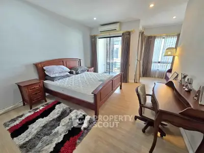 Spacious bedroom with elegant wooden furniture and balcony access in modern apartment.