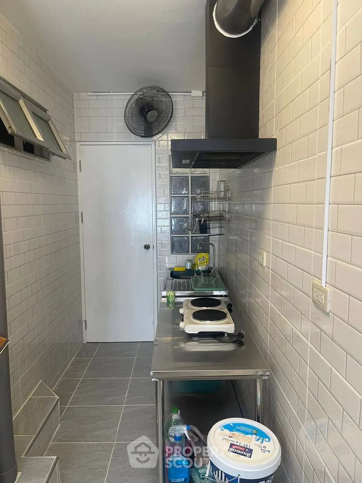Compact kitchen with modern appliances and tiled walls, featuring a sleek countertop and efficient layout.
