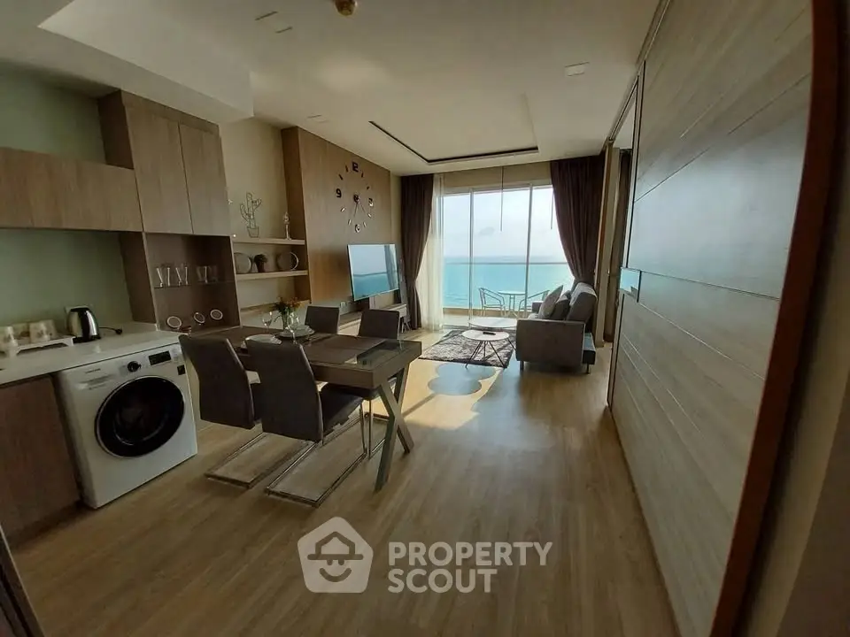 Modern living room with ocean view, stylish furniture, and open kitchen layout.