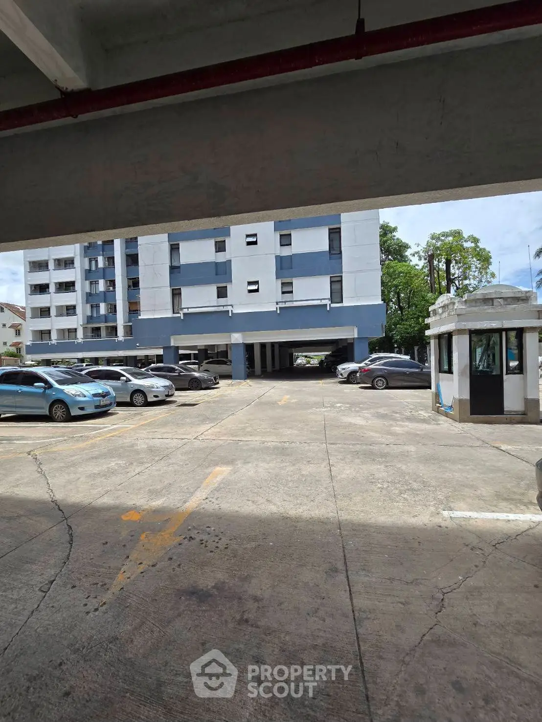 Spacious parking area in front of modern residential building with multiple cars parked.