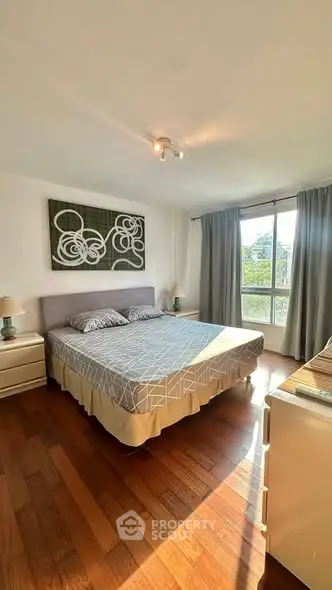 Spacious bedroom with modern decor and large window for natural light.