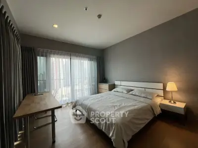 Spacious bedroom with modern decor and large window offering natural light.