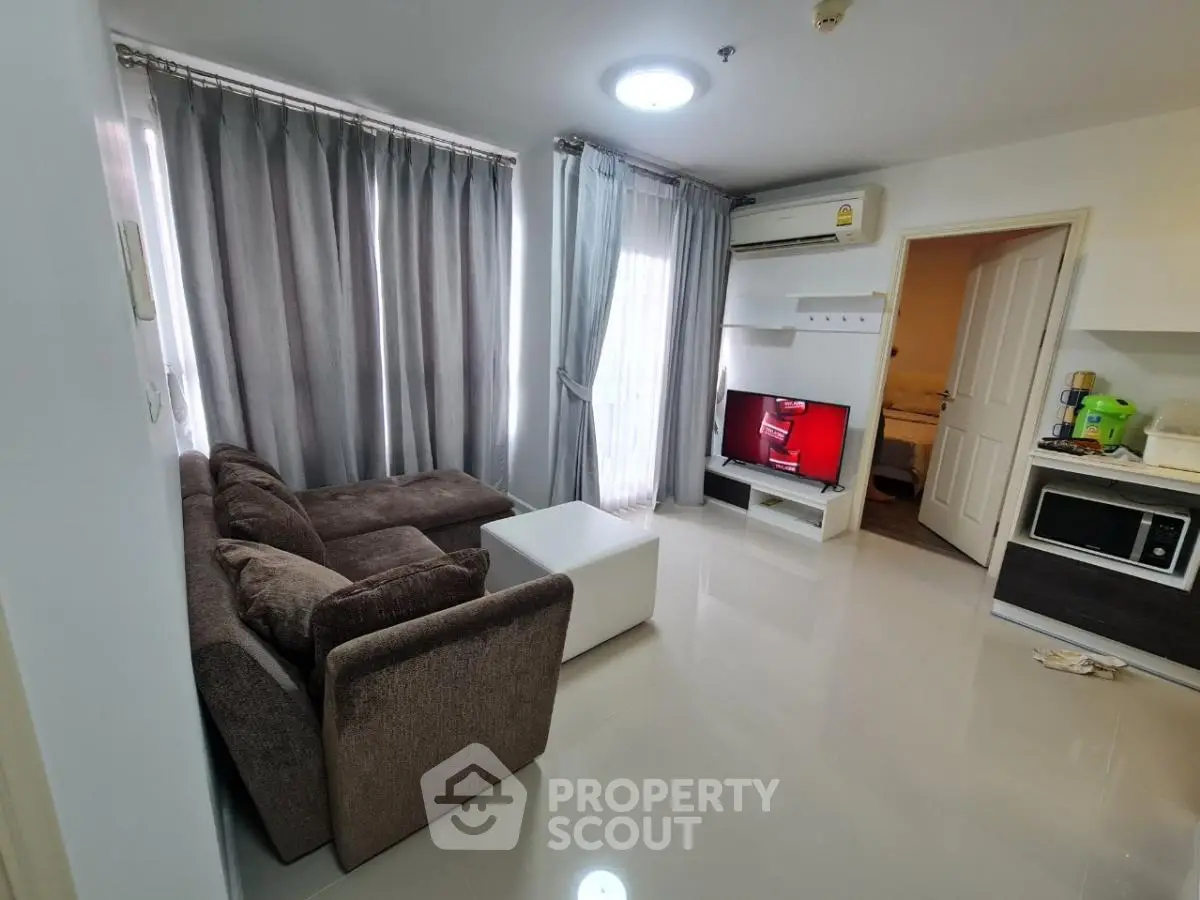 Modern living room with cozy brown sofa, sleek TV setup, and natural light from large windows.