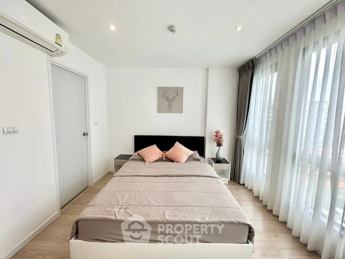 Modern bedroom with large windows and stylish decor in a bright apartment.