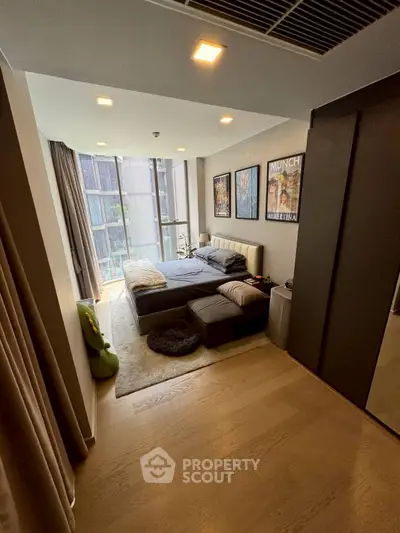 Modern bedroom with large windows and stylish decor in urban apartment.
