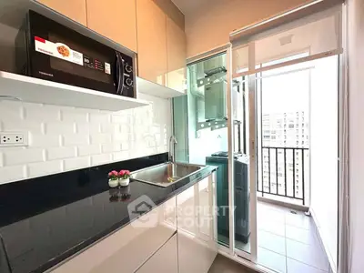 Modern kitchen with sleek cabinets and balcony view in urban apartment