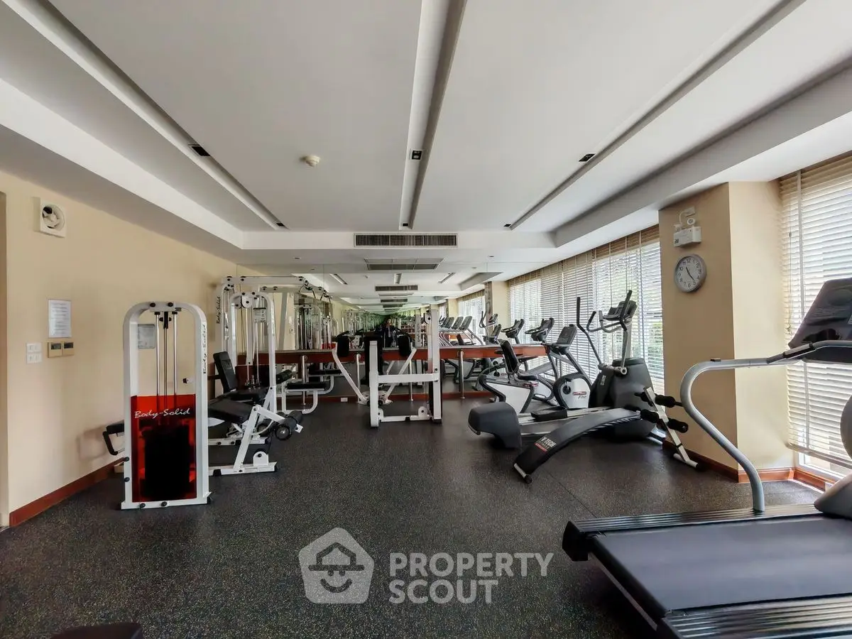 Spacious modern gym with state-of-the-art fitness equipment and large windows for natural light.
