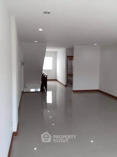 Spacious open-plan living area with glossy tiled floors and bright natural lighting.