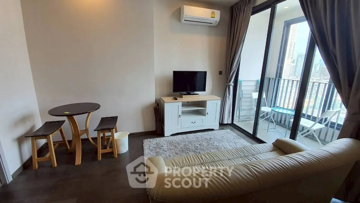 Modern living room with balcony view, featuring cozy seating and compact dining area.