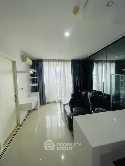 Modern living room with sleek furniture and large windows offering natural light.